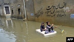 Girls use a temporary raft across a flooded street after heavy monsoon rains in Karachi, Pakistan.