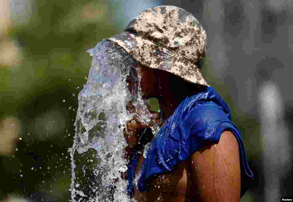 A boy refreshes himself at a fountain during a heatwave that is roasting&nbsp; Europe, in Brussels, Belgium.
