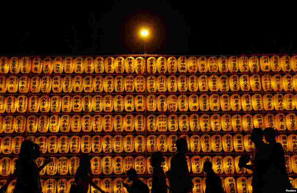 Visitors are silhouetted in front of lanterns during the annual Mitama Festival at the Yasukuni Shrine, where more than 2.4 million war dead are enshrined, in Tokyo, Japan.