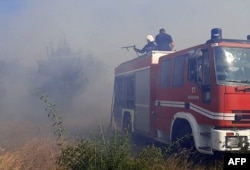 This handout picture released by Ukraine Emergency Service on July 17, 2022 shows firefighters puting out a fire on a wheat field burned as a result of shelling in Mykolaiv region, amid Russian military invasion of Ukraine. (Photo by Ukraine Emergency Ser