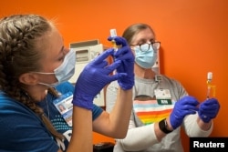 Dr. Emily Drwiega dari University of Illinois Health dan perawat Maggie Butler, menyiapkan vaksin cacar monyet di klinik nirlaba Test Positive Aware Network di Chicago, Illinois, AS, 25 Juli 2022. (REUTERS/Eric Cox)