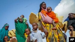 FILE - Somali women and children who fled drought-stricken areas carry their belongings as they arrive at a makeshift camp for the displaced on the outskirts of Mogadishu, Somalia, June 30, 2022. 