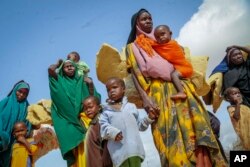 FILE - Somalis who fled drought-stricken areas carry their belongings as they arrive at a makeshift camp for the displaced on the outskirts of Mogadishu, June 30, 2022.