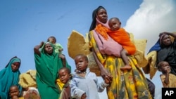 FILE - Somalis who fled drought-stricken areas carry their belongings as they arrive at a makeshift camp for the displaced on the outskirts of Mogadishu, Somalia, on June 30, 2022.