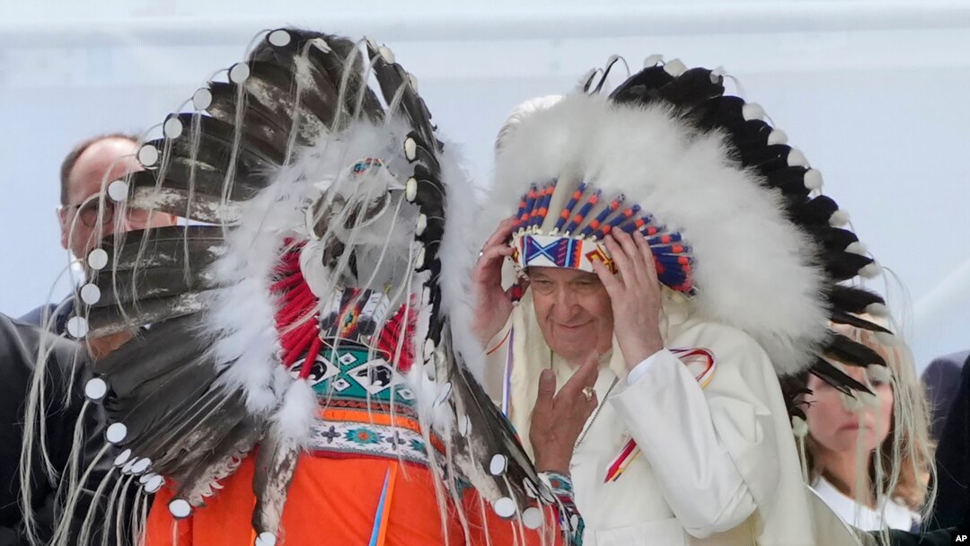 Paus Fransiskus mengenakan penutup kepala suku pribumi Kanada selama pertemuan untuk minta maaf atas penganiayaan dan pelecehan warga pribumi oleh Gereja Katolik, di kota Maskwacis, dekat Edmonton, Kanada (25/7). (Foto: AP) 