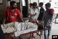 Seorang pria dipindahkan dengan tandu setibanya di Rumah Sakit Sipil Ahmedabad dengan ambulans, 26 Juli 2022, setelah menderita masalah kesehatan karena mengonsumsi minuman keras bajakan. (SAM PANTHAKY / AFP)