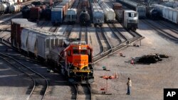 FILE - A BNSF rail worker monitors the departure of a freight train on June 15, 2021, in Galesburg, Illinois. President Joe Biden is expected to name a board of arbitrators to intervene in a freight railroad contract dispute before a July 18, 2022, deadline.