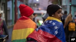 ARCHIVO - Una persona envuelta en una bandera venezolana camina con un grupo de migrantes que salen de la ciudad de Tapachula en el estado de Chiapas, México, a principios del 6 de junio de 2022, después de que el grupo se cansó de esperar para normalizar su estatus.
