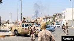 Members of the Libyan armed unit, 444 Brigade, backing the Government of National Unity and its Prime Minister Abdulhamid al-Dbeibah, set up a checkpoint as smoke rises in the background in Ain Zara area in Tripoli, Libya. (File)