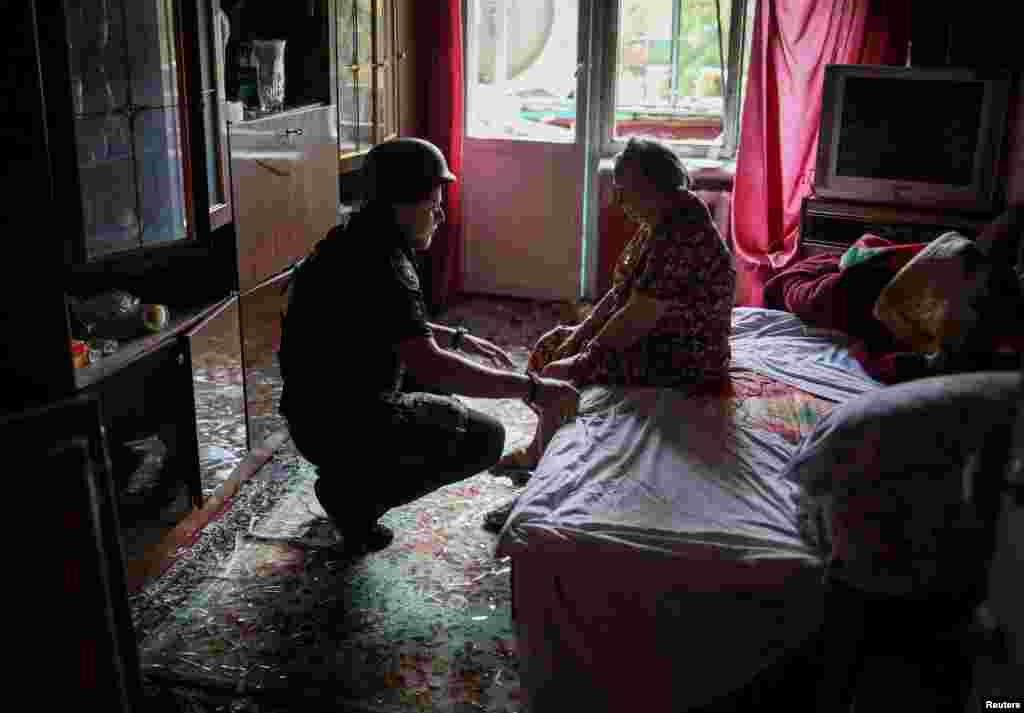 A police officer helps an elderly woman leave her flat in a residential building damaged by a Russian military strike in Kramatorsk, in the Donetsk region of Ukraine.