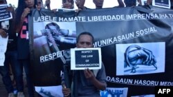 FILE - East Timorese journalist Raimundos Oki holds a placard during a rally to support him, in Dili, May 29, 2017. Charges of defamation against Oki were dropped in that case, but he now is under investigation in a new case, accused of having breached judicial secrecy.