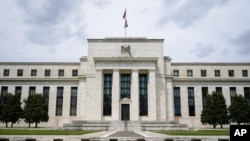 FILE - An American flag flies over the Federal Reserve building in Washington, May 4, 2021.