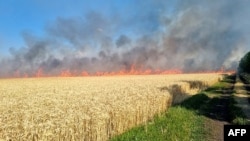This handout picture released by Ukraine Emergency Service on July 17, 2022 shows firefighters puting out a fire on a wheat field burned as a result of shelling in Mykolaiv region, amid Russian military invasion of Ukraine. (Photo by Ukraine Emergency Ser