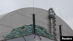 FILE - A sandbag barricade sits on a building close to the New Safe Confinement (NSC) structure over the old sarcophagus covering the damaged fourth reactor at the Chernobyl Nuclear Power Plant, in Chernobyl, Ukraine April 16, 2022.