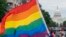 FILE - With the US Capitol in the background, a person waves a rainbow flag as they participant in a rally in support of the LGBTQIA+ community at Freedom Plaza, June 12, 2021, in Washington. 