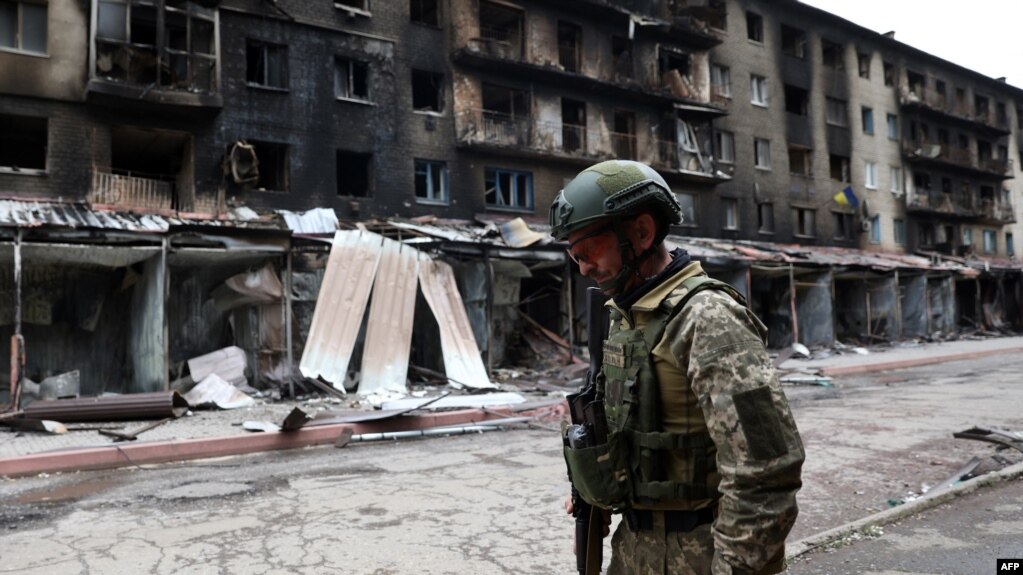 一名乌克兰军人经过顿涅茨克地区塞维尔斯克城镇的被毁楼房（2022年7月22日）(photo:VOA)