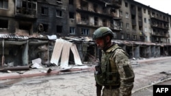 一名乌克兰军人经过顿涅茨克地区塞维尔斯克城镇的被毁楼房（2022年7月22日）