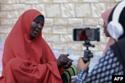 Dua jurnalis perempuan Bilan Media, tengah mewawancarai perempuan pengelola restoran di sebuah pasar di Mogadishu, 22 Mei 2022.(Hasan Ali Elmi / AFP)