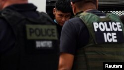 Un migrante es escoltado por agentes del Servicio de Inmigración y Control de Aduanas (ICE) de EEUU para ser llevados a México, en Laredo, Texas, el15 de junio de 2022.
