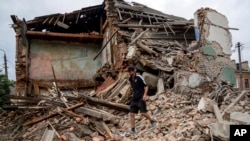 Un homme cherche les documents d'un ami blessé dans les décombres d'un immeuble détruit après un bombardement russe dans un quartier résidentiel de Chuhuiv, région de Kharkiv, Ukraine, le 16 juillet 2022.