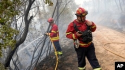Un bombero habla por la radio mientras trabaja para prevenir que un incendio forestal arrase con nuevas zonas en la localidad de Rebolo, cerca de Ansiao, en el centro de Portugal, el jueves 14 de julio de 2022. (AP Foto/Armando Franca)