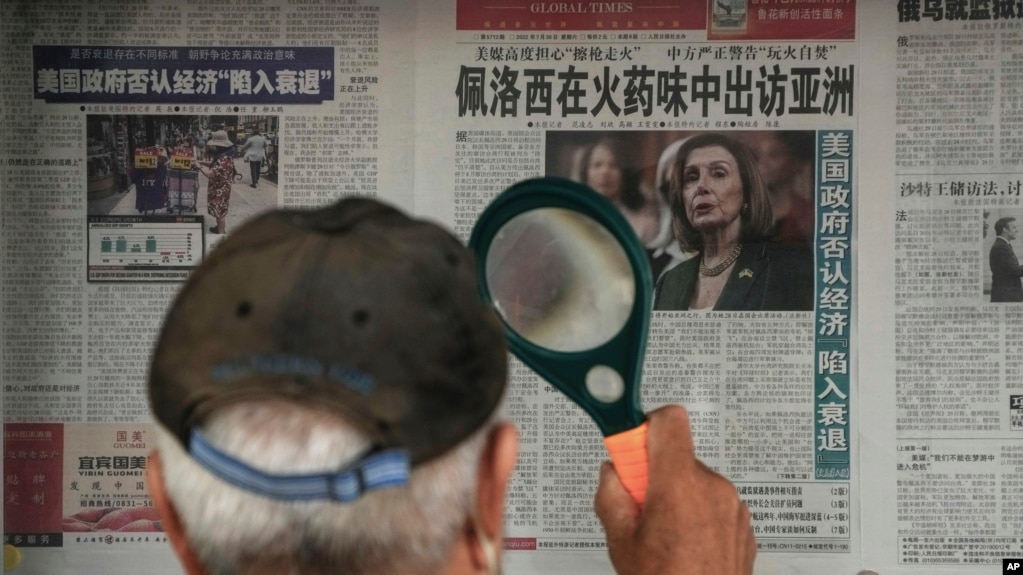 北京一位老者站在读报栏前用放大镜看包。报纸头版文章报道美国众议院议长佩洛西访问亚洲的消息。