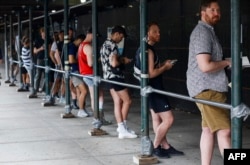 People wait in line to receive the monkeypox vaccine before the opening of a new mass vaccination site at the Bushwick Education Campus in Brooklyn, New York, July 17, 2022.