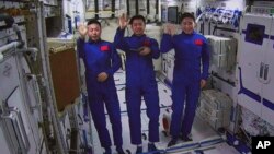 In this photo released by Xinhua News Agency, an image taken off the screen at the Beijing Aerospace Control Center, shows Chinese astronauts from left, Cai Xuzhe, Chen Dong and Liu Yang wave from inside the Wentian lab module on Monday, July 25, 2022. 