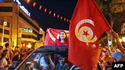 Supporters of President Kais Saied rejoice on Habib Bourguiba Avenue in Tunis on July 26, 2022 after the projected outcome was announced. - Saied celebrated the almost certain victory of the "yes" vote on a new constitution strengthening the power of the head of state.