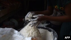 FILE - A vendor measures wheat flour in a cup for retail at a market in Ibafo, Ogun State, southwest Nigeria. Taken 3.14.2022