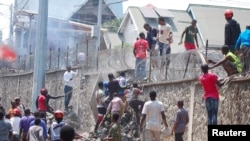 Congolese protesters scale the perimeter wall of the compound of United Nations peacekeeping force's warehouse in Goma, in the North Kivu province of the Democratic Republic of Congo, July 26, 2022.