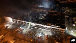 FILE - Ukrainian State Emergency Service firefighters work to extinguish a fire at a shopping mall burned after a rocket attack in Kremenchuk, Ukraine. Fact-checkers debunked Russian claims that the mall was not a civilian site.