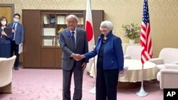 La secretaria del Tesoro de Estados Unidos, Janet Yellen, a la derecha, y el ministro de Finanzas de Japón, Shunichi Suzuki, se dan la mano durante su reunión en el Ministerio de Finanzas en Tokio, el martes 12 de julio de 2022.