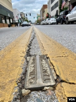 These brass markers run down the center of State Street, serving as the official border between the states.  They differentiate Bristol, Tennessee, where abortion is prohibited, from Bristol, Virginia, where they are legal.  (Caroline Presutti/VOA)