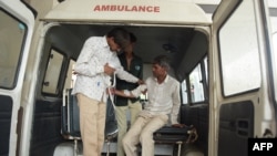 Seorang pria (kanan) tiba dengan ambulans di Rumah Sakit Sipil di Ahmedabad pada 26 Juli 2022, setelah menderita masalah kesehatan akibat mengonsumsi minuman keras bajakan. (SAM PANTHAKY / AFP)