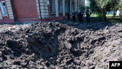 Police experts examine a crater after a Russian missile strike near a school on the outskirts of Kharkiv, July 15, 2022, amid the Russian military invasion of Ukraine.