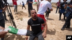 FILE - An injured Palestinian protester who was attacked by an Israeli settler waits for medical help on a road near the Jewish settlement of Mezbi yair, Masafer Yatta, West Bank, May 13, 2022.