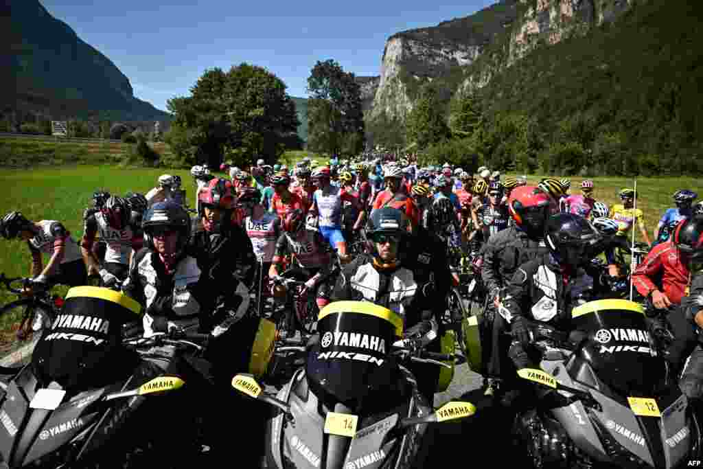 The pack of riders is temporarily stopped by race regulators, seen at front, because protests on the race route during the 10th stage of the 109th edition of the Tour de France cycling race, between Morzine and Megeve, in the French Alps.