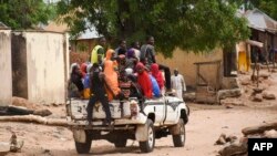 FILE: Residents leave the Kukawa village in Plateau State on April 12, 2022 after their houses were burnt down during an attack by bandits. - President Muhammadu Buhari vowed there would be no mercy for those perpetrating these attacks.