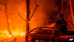 Un bombero echa agua en un incendio forestal en La Test-de-Buch, suroeste de Francia, el lunes 18 de julio de 2022. (SDIS 33 vía AP)