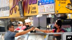 Sejumlah pekerja di salah satu stan makanan di Grand Central Market Los Angeles, tampak mengenakan masker ketika melayani para konsumen yang datang pada 13 Juli 2022. (Foto: AP/Marcio Jose Sanchez)