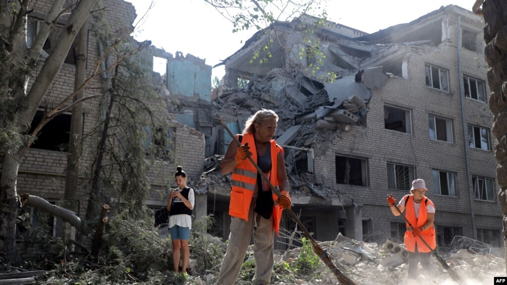 在俄军炮击乌克兰的尼古拉耶夫后,社区工作人员在一座被毁的建筑物清扫。(2022年8月22日)(photo:VOA)