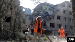 在俄军炮击乌克兰的尼古拉耶夫后,社区工作人员在一座被毁的建筑物清扫。(2022年8月22日)