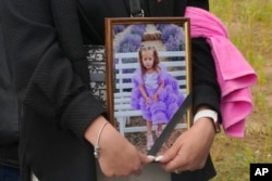 A woman holds a portrait of Liza, a girl with Down syndrome killed days earlier by a Russian missile, during her funeral in Vinnytsia, Ukraine, July 17, 2022.