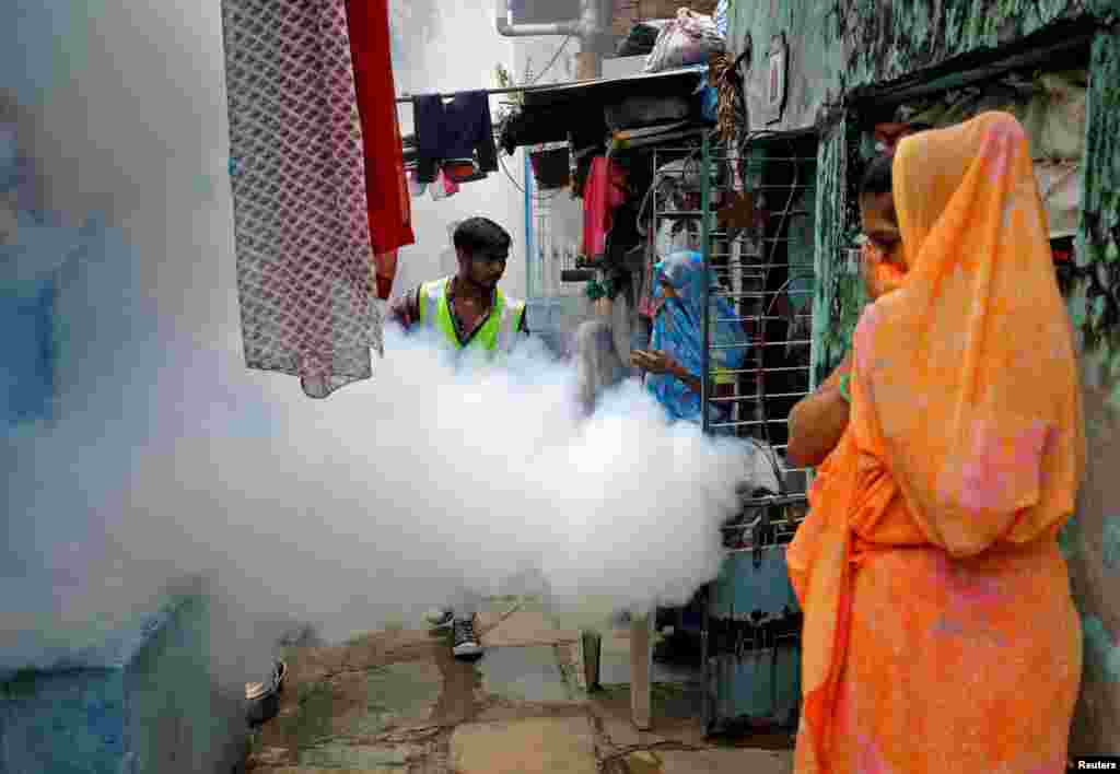 Women cover their faces as a health worker fumigates a residential neighborhood to prevent the spread of mosquito-borne diseases following recent rainfall and water logging, in Ahmedabad, India.