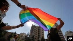 FILE - Activists from the LGBTQ community in Lebanon shout slogans and hold up a rainbow flags as they march calling on the government for more rights in the country gripped by economic and financial crisis, June 27, 2020. 