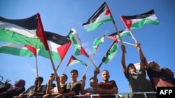 Sejumlah demonstran asal Palestina mengibarkan bendera Palestina dalam aksi protes menentang kunjungan Presiden AS Joe Biden ke Israel. Aksi tersebut digelar di Kota Gaza pada 14 Juli 2022. (Foto: AFP/Mohammed Abed)