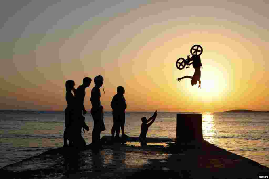 A biker performs tricks at Kavouri beach during a heatwave near Athens, Greece, July 24, 2022. 