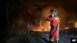 En esta foto proporcionada por la Unidad Militar de Emergencias (UME) de España, un bombero trabaja para extinguir un incendio forestal en la zona de Monsagro, en el oeste de España, en la madrugada del sábado 16 de julio de 2022. (UME/J.de Oro vía AP)