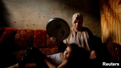 Seorang perempuan Palestina mengipasi putrinya dengan nampan di tengah gelombang udara panas dan pemadaman listrik yang berkepanjangan di Kota Gaza, Jalur Gaza akibat blokade Israel.